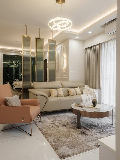 This living room at DNR Arista is a masterclass in modern elegance. Warm neutrals, layered textures, and rose gold accents create a space that is both grand and comfortable, with fluted glass panels providing a subtle separation.