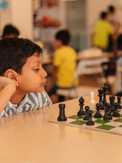 A young chess player studies the board, a perfect picture of focus and strategic thinking. Our classes help children develop patience and foresight.