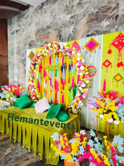 Another angle of the indoor Mehendi decor, showing the colorful artificial flowers and traditional kite decorations that add a playful touch.