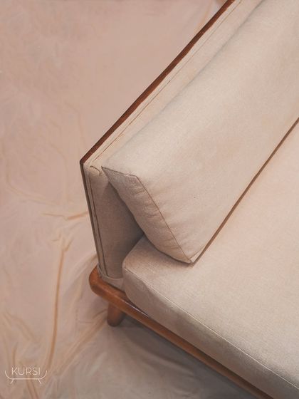 A detail of the 'Halo' sofa, showing the plush cushions and the solid teak wood frame. Each curve tells a story, every detail whispers elegance.