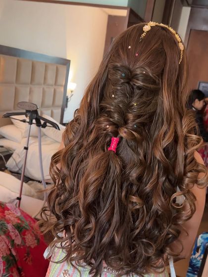 A mermaid-inspired half-up style with curls and a fishtail braid detail. The small hair accessories add a touch of sparkle to this dreamy look.