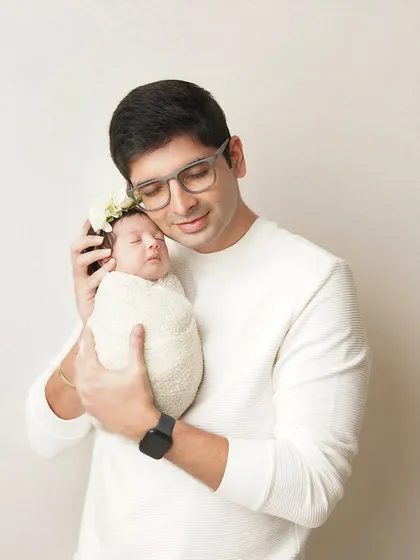 A father holds his swaddled newborn close, a picture of gentle strength and love. These father-child portraits are always a favorite.