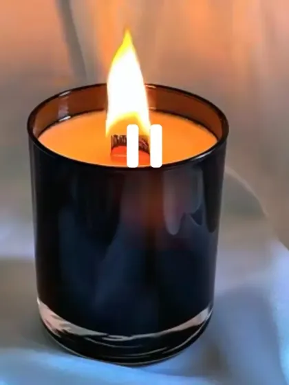 A lit black jar candle with a wooden wick, which creates a lovely crackling sound.
