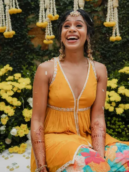 A radiant bride enjoying her Haldi ceremony. The bright orange and floral patiala, paired with gota jewelry, created a look that was full of life and perfect for the occasion.