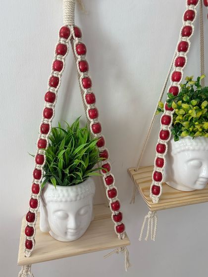 A close-up of the pink beaded planter shelf, showing the detail of the knots and the vibrant color of the beads.