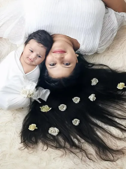 A lovely overhead shot of a mother and her newborn lying коммерческих, with the mother's hair decorated with flowers.