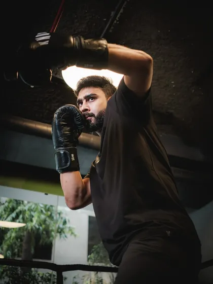 A focused shot of a client ready to strike during a boxing session. The intensity in his eyes shows the mental and physical engagement required for the sport.