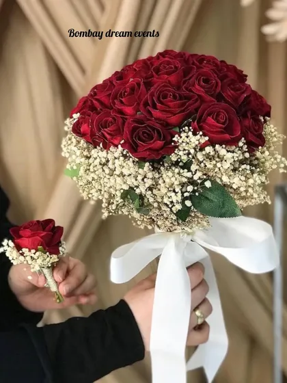 A stunning red rose bridal bouquet, accented with baby's breath and paired with a matching boutonnière for the groom.