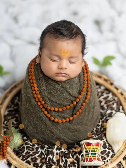 A peaceful close-up of the baby as Mahadev, showing the detail of the rudraksha beads and the serene expression.