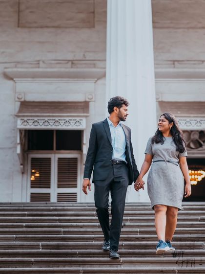 A full-length shot of the couple holding hands while walking down grand steps, blending a casual style with an elegant location.
