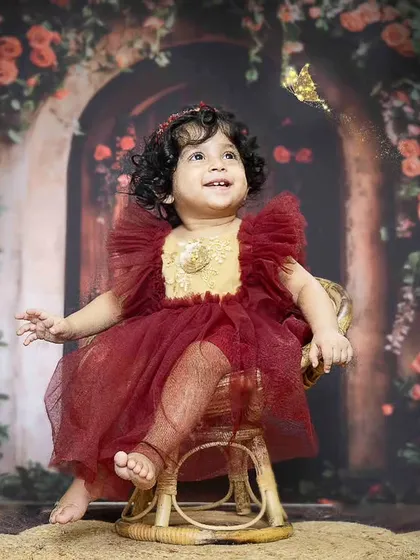 Love and magic in this little girl's world. Her first birthday portrait features a beautiful red dress and an enchanting floral backdrop.