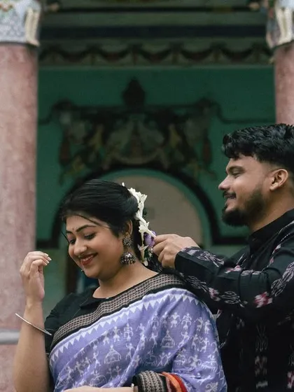 A duplicate of image 43, this close-up captures the groom tenderly adjusting a flower in the bride's hair, a simple gesture filled with love, set against historic pillars.