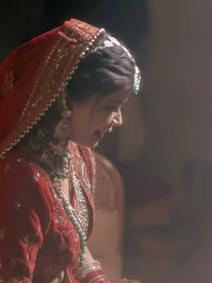 A soft-focus, dreamy portrait of the bride, capturing a candid smile. The gentle lighting gives the photo a romantic and ethereal feel.