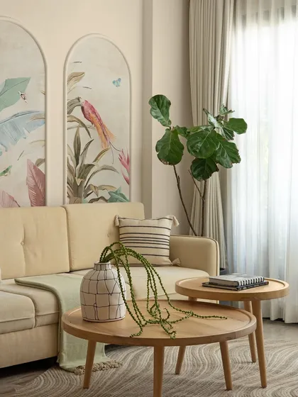 A close-up of the living area, where natural light from the large window illuminates the space. The organic shapes of the plants and the gentle curves of the furniture create a peaceful and harmonious atmosphere.