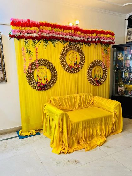 Another perspective of the haldi decoration setup inside a client's home. The bright colors and floral elements create a festive atmosphere for your pre-wedding events.