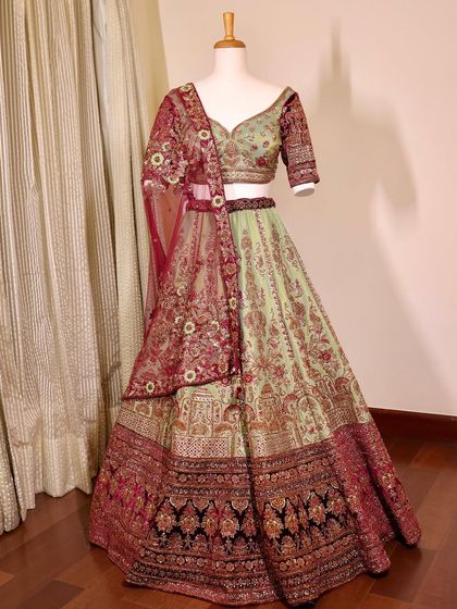 The full mint green and maroon lehenga on a mannequin. This view shows the beautiful contrast and the overall design of this unique bridal piece.