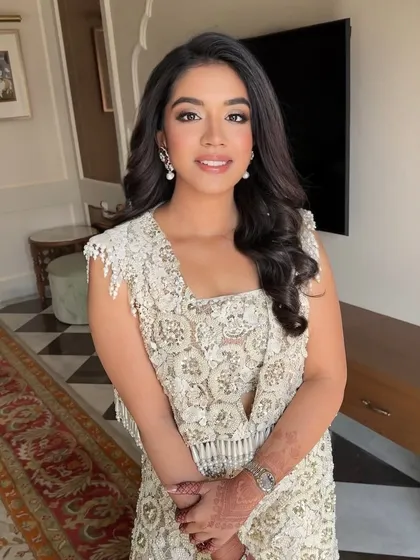 Golden hour glow meets intricate elegance. This bride's look features soft waves and our flawless glam makeup, perfect for her detailed ivory outfit.