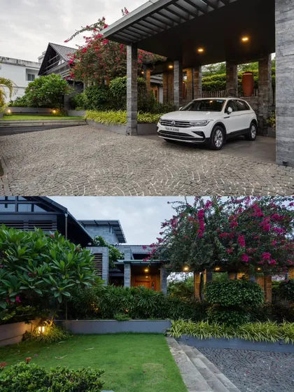 The entrance to the residence is lush and green, with a stone-paved driveway leading to a modern carport framed by bougainvillea.