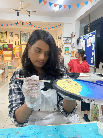 A participant works on her resin beach art, carefully placing elements to create her desired scene.