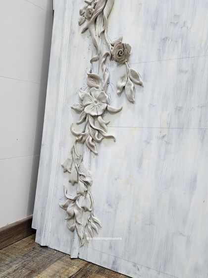 A side view of the South Mount mural, showing the high relief of the sculpted flowers and ribbons. This dimensionality allows the artwork to cast shadows and change its appearance throughout the day.