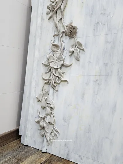 A side view of the South Mount mural, showing the high relief of the sculpted flowers and ribbons. This dimensionality allows the artwork to cast shadows and change its appearance throughout the day.