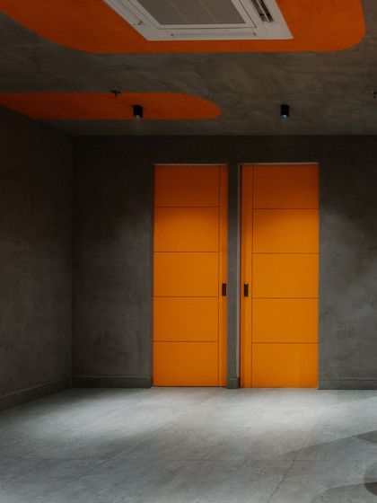 A pair of bright orange doors adds a playful and unexpected element to the basement's otherwise industrial-inspired grey walls.