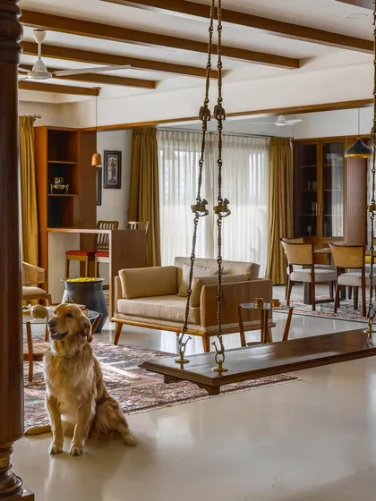 A candid moment in the 'Vasudhalayah' living room, where the family pet sits before the expansive communal space featuring a traditional swing and custom furniture.
