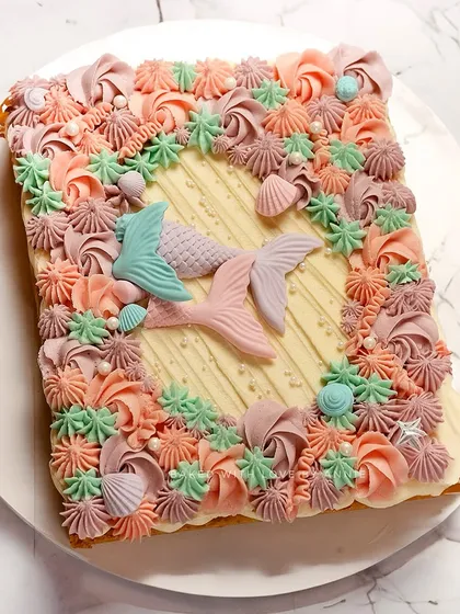 A slice of oceanic delight. This egg-free vanilla sheet cake is decorated with magical mermaid tails and fondant shells, perfect for an intimate theme party.