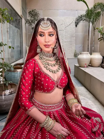 The complete bridal look with the dupatta. The sheer red veil adds a layer of romance and tradition to the overall styling.
