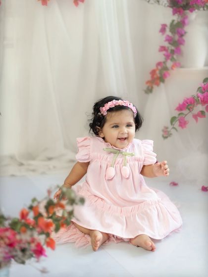 A joyful smile from a ten-month-old baby in a lovely pink dress. The floral theme for this milestone shoot is so bright and cheerful.