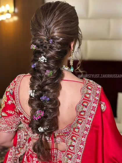 A thick, voluminous fishtail braid decorated with small, colorful fresh flowers. This hairstyle is ideal for a Mehendi or Haldi ceremony, adding a touch of natural beauty to the look.