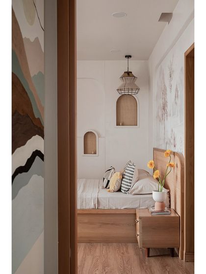 A sneak peek into the master bedroom, framed by a curved doorway. The design is all about calm, earthy tones and rich natural textures, with rattan details and arched niches adding depth and character.
