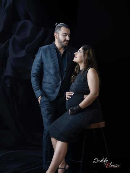 A beautifully composed portrait of a couple looking at each other. The elegant posing and dark, formal wear make this a very sophisticated maternity photograph.