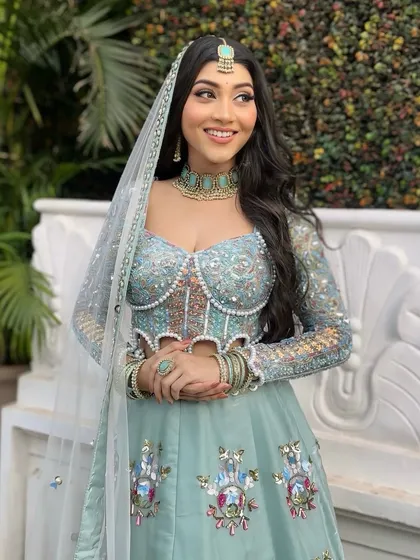 The complete look, showing the flow of the beautiful powder blue lehenga. The soft makeup and hair perfectly complement the intricate design of the outfit.
