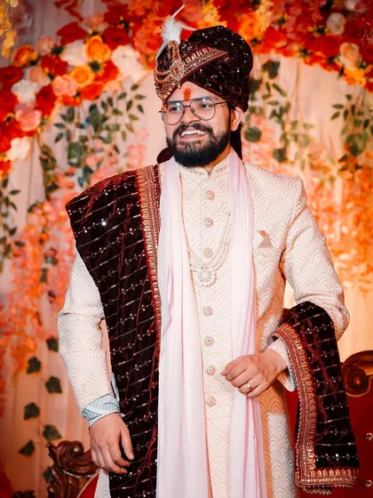 A stylish portrait of the groom looking sharp in his wedding sherwani. His relaxed pose and confident smile make for a great shot.