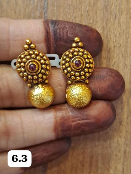 A pair of circular antique gold-plated earrings with a textured golden ball drop. These are a classic design that can be worn with any outfit.