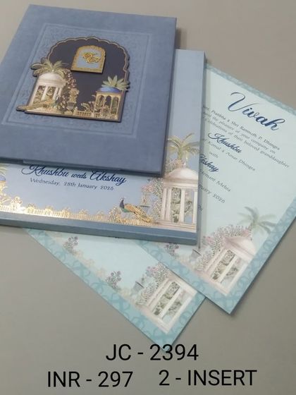 This velvet-finish invitation in a soft blue features a 3D jharokha with gold foil details. The premium texture and design make it a truly luxurious choice.