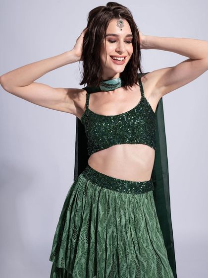 A fun and playful shot in a green sequined lehenga. The makeup is bright and fresh, with a focus on glowing skin and a happy, radiant vibe.
