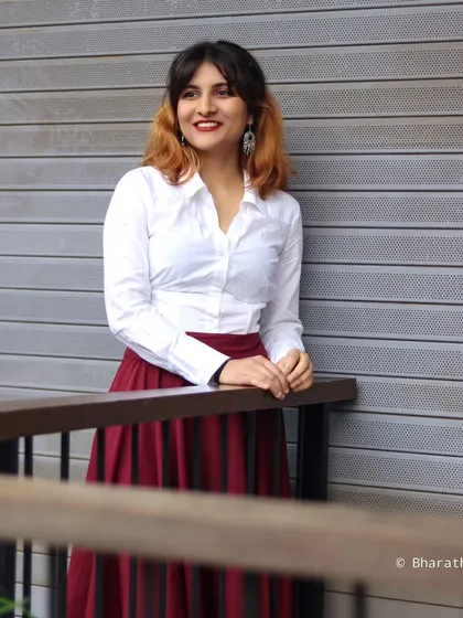 A three-quarter shot of the model leaning against a railing, with a happy and engaging expression.