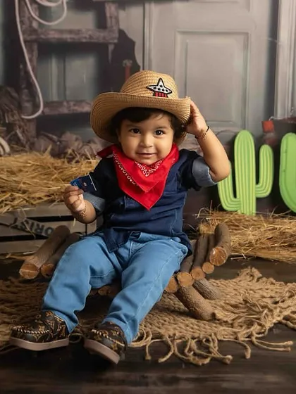 Tipping his hat like a true gentleman. The rustic barn backdrop completes this adorable cowboy theme.