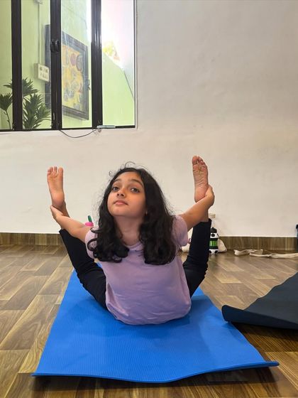 This young yogini shows incredible flexibility in this variation of Dhanurasana, or bow pose. Her focus and determination are an inspiration to see in class.