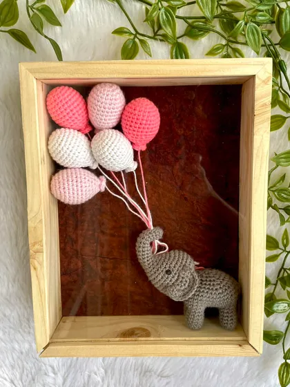 My crochet creations aren't just for cuddling, they can also be beautiful decor for your home. This framed piece features a tiny elephant holding a bouquet of balloons, perfect for a nursery or as a unique baby shower gift. Each frame can be personalized with a name.