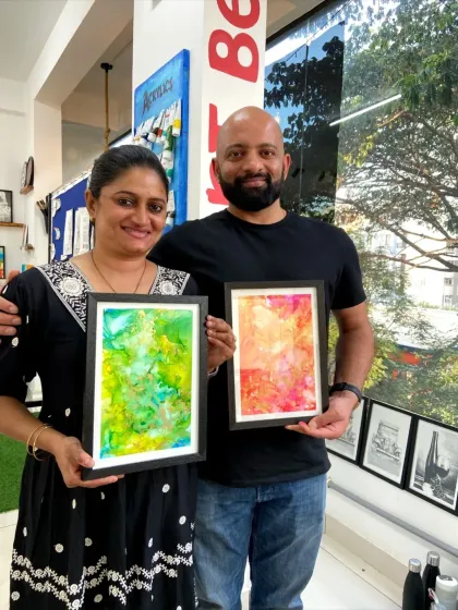 A couple proudly displays their framed alcohol ink paintings. The vibrant and unpredictable nature of this medium makes every piece unique.
