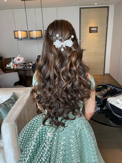 A full view of the hairstyle from the back. The soft curls and pretty accessory create a very romantic and feminine look.