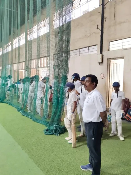 A coach keenly observes a young batsman during net practice at the trials. Every player gets a fair opportunity to show their skills.