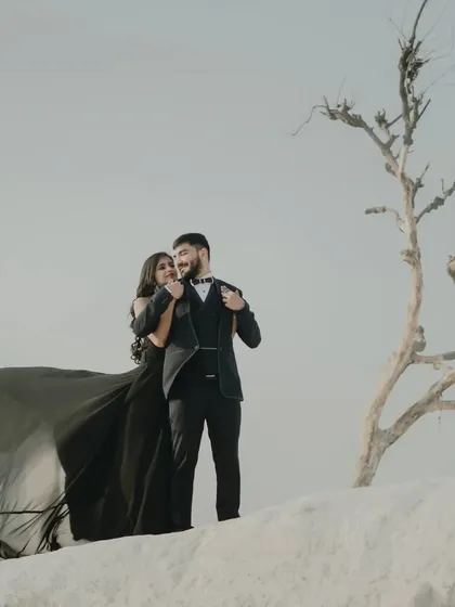 A stylish and modern pre-wedding photo. The couple's all-black attire and the stark, minimalist background create a very chic and editorial look.
