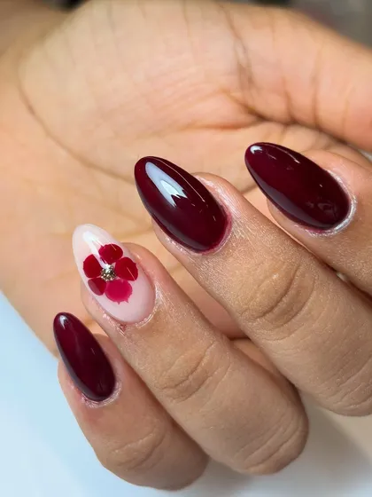 Elegance in the details. This look combines a rich, glossy berry polish with a delicate, hand-placed dried flower accent nail. It’s a sophisticated design that’s perfect for any special occasion.