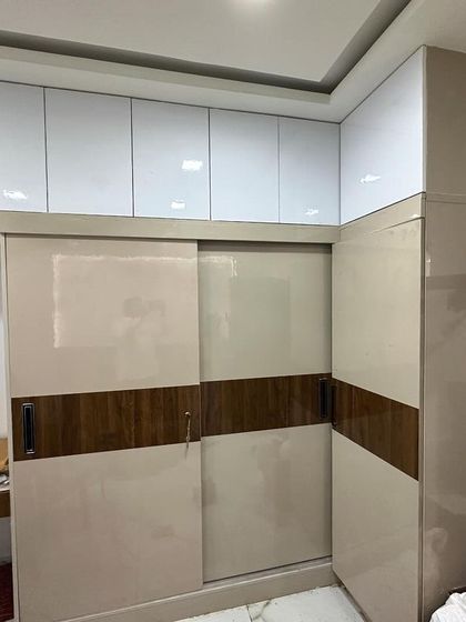 A sliding wardrobe with a mix of beige and wood-finish panels, photographed during a housewarming.