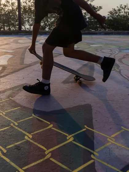 A close-up of a skater's feet on the painted surface of the skatepark, showing the interaction between the art and its users.