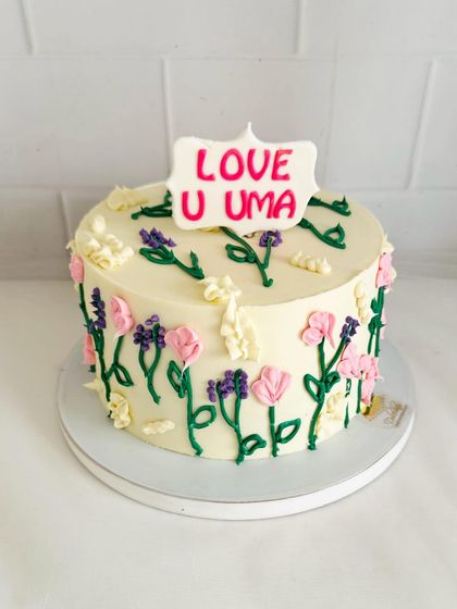 A charming cake with hand-piped wildflowers, giving it a rustic and sweet "meadow" look.